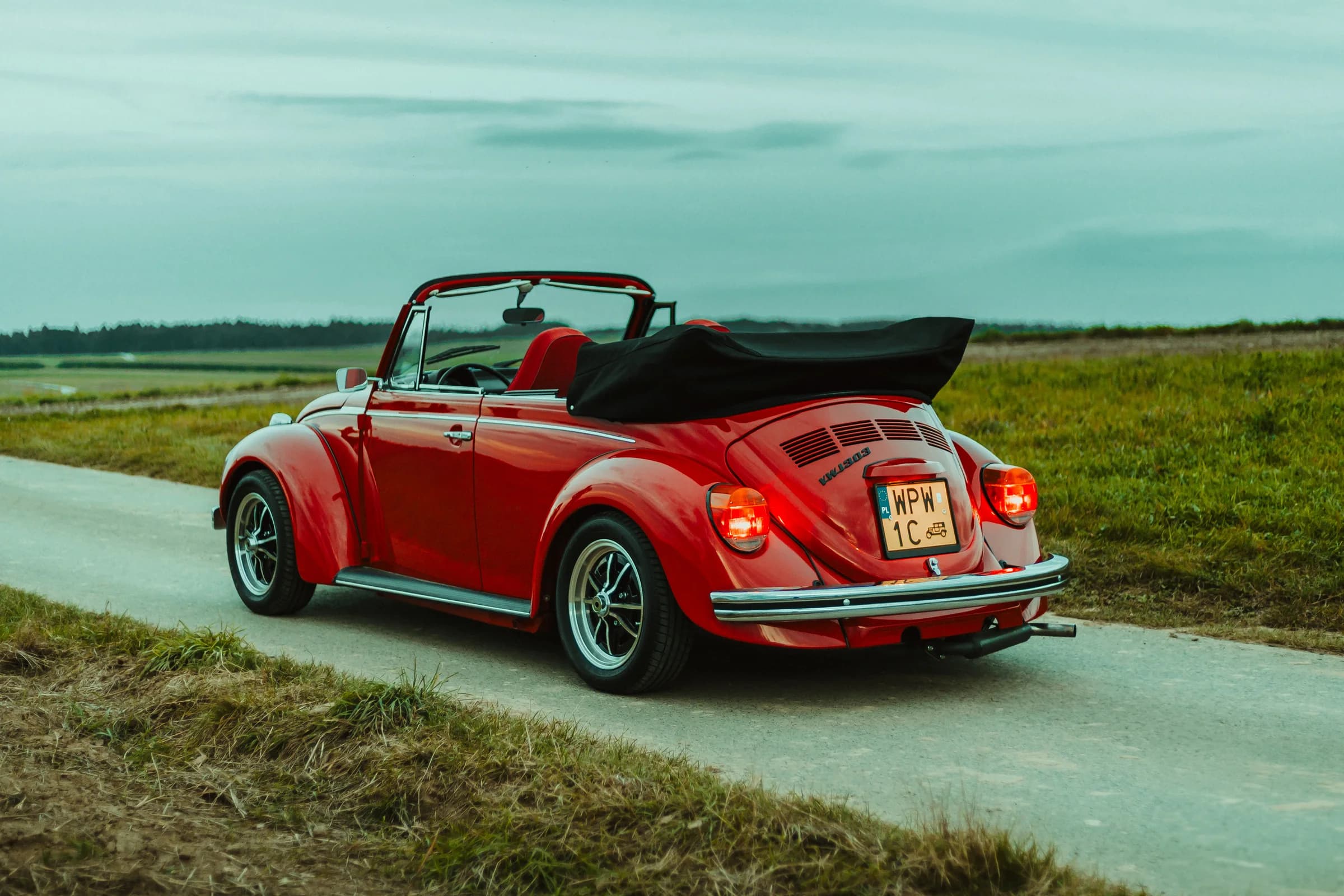 Czerwony Volkswagen Garbus Cabrio na wiejskiej drodze